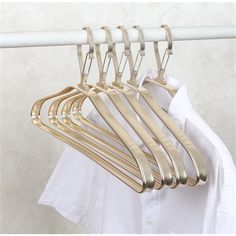 gold colored clothes hangers on a white coat rack in front of a plain white shirt