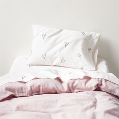 an unmade bed with pink sheets and white pillowcases on top of it