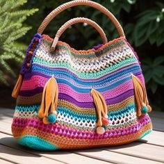 a multicolored crocheted bag sitting on top of a wooden table next to a plant