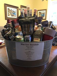 a metal bucket filled with lots of different types of food and drinks on top of a wooden table