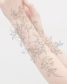 a woman's arm with flowers and leaves on the wrist, in front of a white background