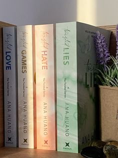 three books are sitting on a shelf next to a potted plant and other items