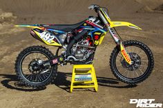 a dirt bike parked on top of a yellow step stool in the middle of a dirt field