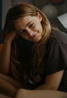 a woman sitting on top of a wooden bench next to a window with her hand on her head