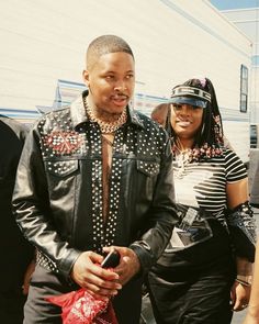 a man and woman standing next to each other in front of a white building with people around them