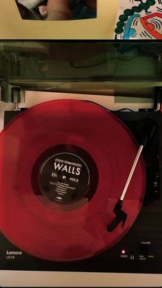 a red record player sitting on top of a table next to a wall with pictures