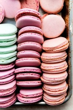 there are many pink and green macaroons in the tray