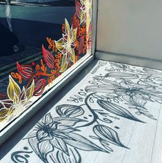 the shadow of a person walking past a window with flowers painted on it's side