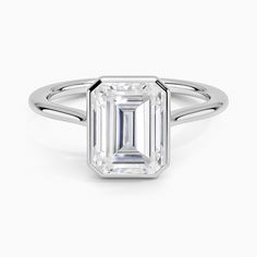 an emerald - cut diamond ring with a thin band on the side, set in 18k white gold