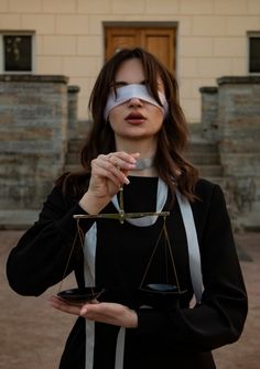 a woman with blindfolded hands holding a scale and an hourglass