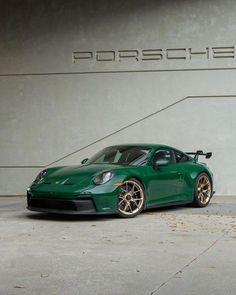 a green sports car parked in front of a porsche logo