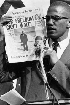 a man reading a newspaper while holding a microphone