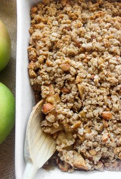 a casserole dish with apples and crumbled toppings in the background