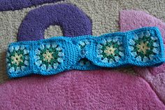 two crocheted headbands with flowers on them laying on the floor next to each other