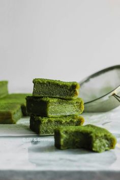 some green food is sitting on a table next to a spoon and a scooper