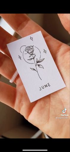 someone is holding a card with a rose on it and the words june written in black ink