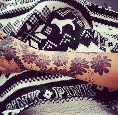 a woman's arm covered in tattoos with flowers on the top and bottom of it