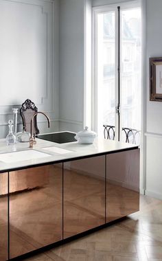 a kitchen with white walls and wooden flooring next to an open window on the wall