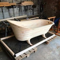 a wooden bathtub sitting on top of a piece of plywood in a workshop