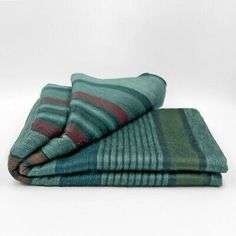 three green and red striped towels folded on top of each other in front of a white background