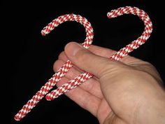 a hand holding a candy cane in the shape of a letter s on a black background