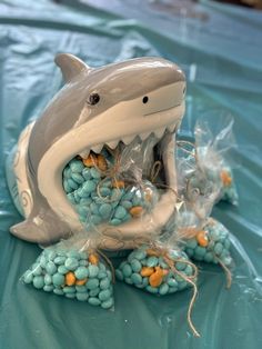 a plastic shark with its mouth open sitting on top of some blue candy candies