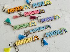 several key chains with different colored tassels and name tags on them sitting on a marble surface