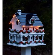 a white bird house with lights on it's roof and windows decorated for christmas