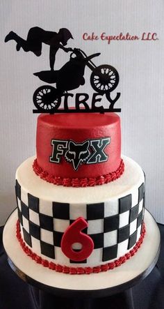 a three tiered cake decorated with a motorcycle and checkered design on the top