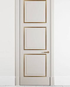 an open white door with gold trim and two square panels on the bottom half of it