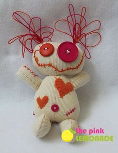 a white stuffed animal with red hair and buttons