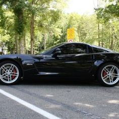 a black sports car is parked on the side of the road in front of some trees