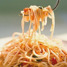 someone is eating spaghetti from a white plate