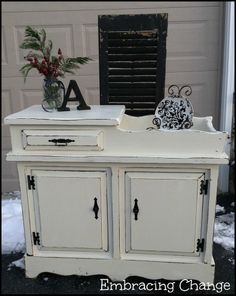 an old dresser is painted white with black accents