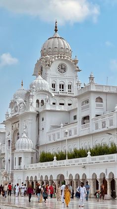 many people are walking around in front of a white building