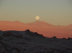 the moon is setting over some mountains in the distance with no one visible on it