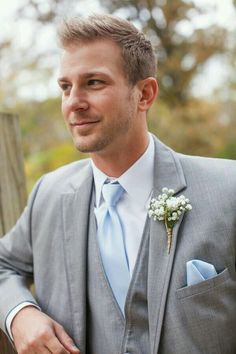 a man in a gray suit with a blue tie and flower boutonniere