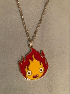 a red and yellow necklace with a cartoon character on it's face hanging from a chain