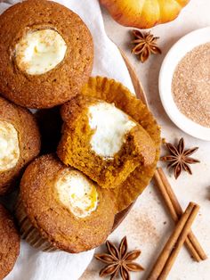 pumpkin spice muffins with cream cheese in the middle and cinnamon sticks around them