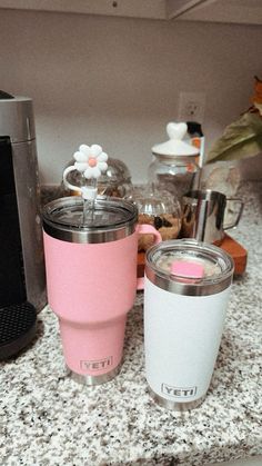 a pink and white coffee cup sitting on top of a counter next to a blender