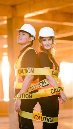 two people wearing hard hats and yellow caution tape