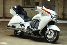 a white motorcycle parked in front of a brick building