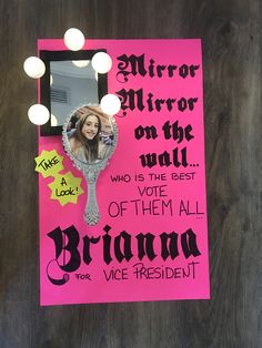 a mirror on the wall that has been decorated with pink paper and black lettering, along with an image of a woman's face