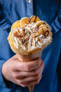 a person holding an ice cream cone with bananas and whipped cream