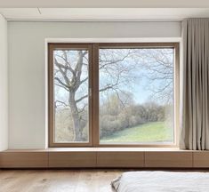 an empty bedroom with two large windows overlooking a field