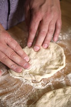 a person kneading dough on top of a wooden table