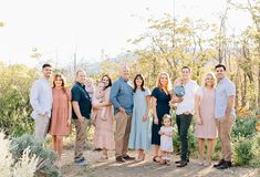 a group of people standing next to each other in front of trees and bushes on a dirt road