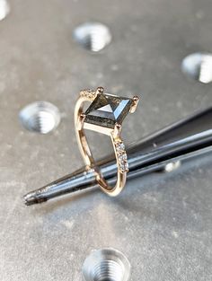 a diamond ring sitting on top of a metal table next to some screwdrivers