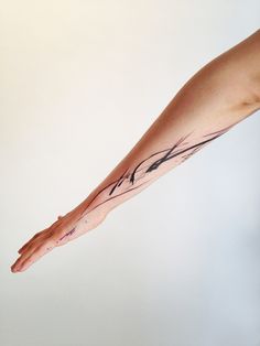 a woman's arm with a tattoo on it and her hand holding something in the air