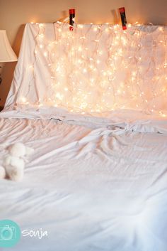 a bed with lights on the headboard and two teddy bears laying on it's side